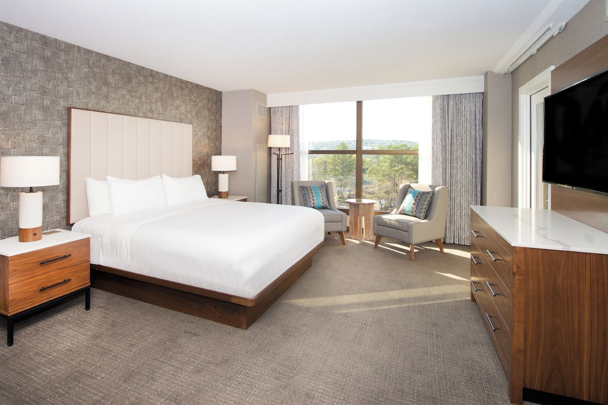 A hotel room with a large bed, a TV, a desk, and a chair.