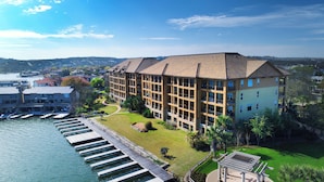 A multi-story hotel with a waterfront view, featuring a dock with boats, a well-maintained lawn, and a clear sky. - Horseshoe Bay Resort (Horseshoe Bay)