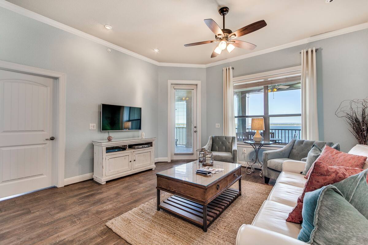 A living room with a ceiling fan, a television, a white sofa, and a coffee table.