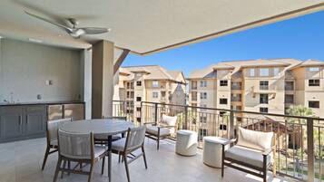 A balcony with a dining set and a view of neighboring buildings.
