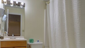 A bathroom with a toilet, sink, vanity, and bathtub. - Classic Inn (Saco)