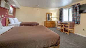 A hotel room with two beds, a desk with a chair, a dresser, a mirror, and a TV on the wall. - Classic Inn (Saco)