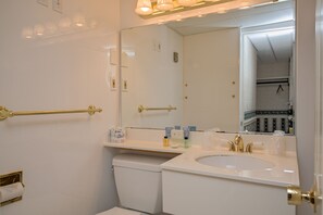 A bathroom with a white sink, a mirror, a towel rack, and a toilet.