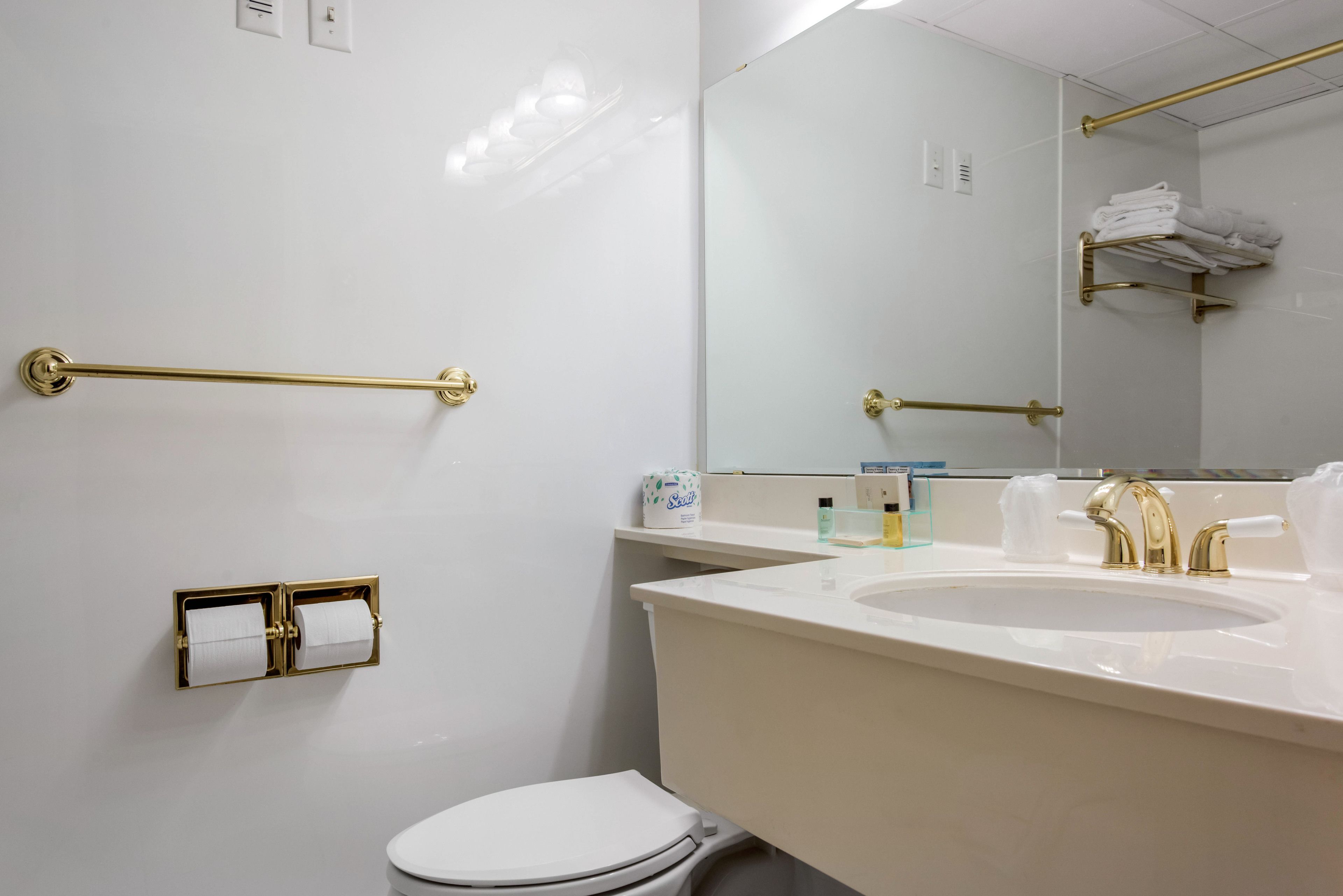 Un baño moderno con un lavamanos blanco, detalles dorados y un inodoro.