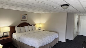 Habitación de hotel con una cama, dos lámparas de noche, un cuadro en la pared y un aplique de techo.