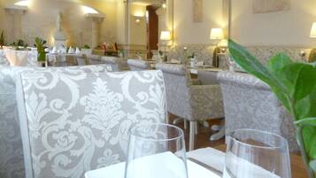 Ein Restaurant mit gedeckten Tischen, mit gemusterten Polstern und klassischer Inneneinrichtung.