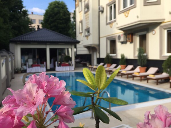 A pool area with lounge chairs and a gazebo.