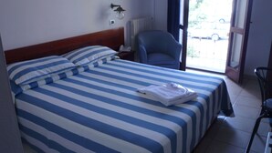 Habitación de hotel con cama, una silla, teléfono y vistas al exterior.