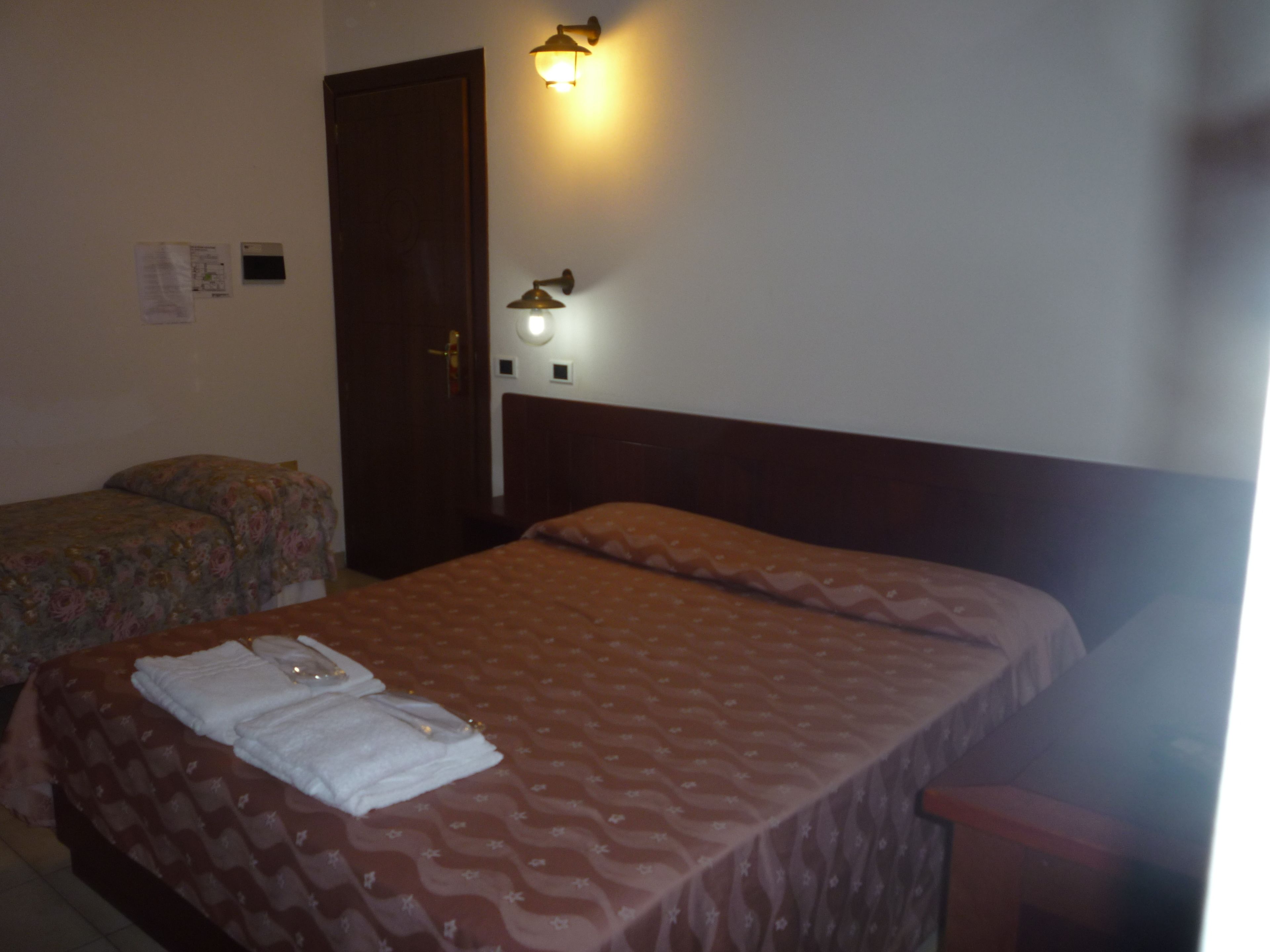 Un dormitorio con dos camas, un cabecero de madera y una lámpara de pared.
