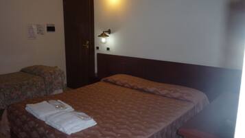 Ein Schlafzimmer mit zwei Betten, einem Holzkopfstück und einer Wandleuchte.