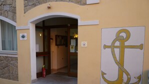 Fachada de edificio de piedra, con un gran mural de un ancla y un extintor cerca de la puerta.