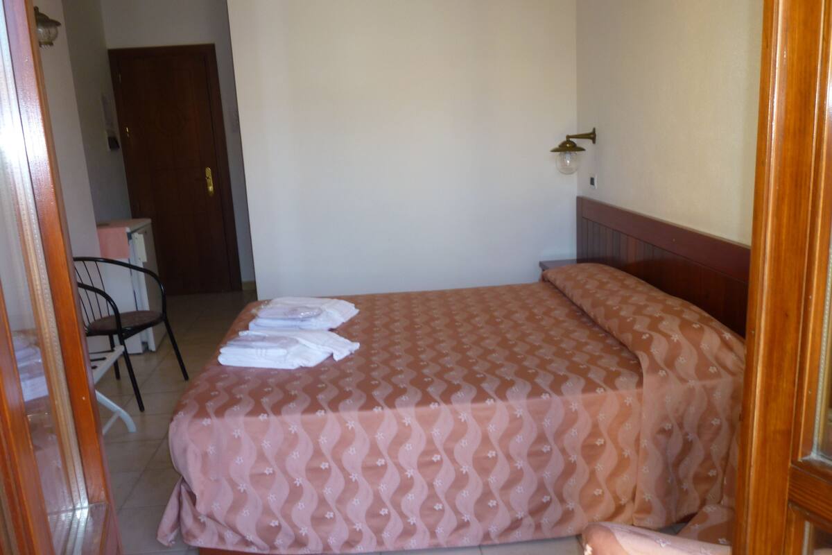 Una habitación de hotel con una cama, una silla y un escritorio.