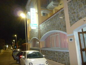 Un hotel con fachada de piedra, un letrero de neón y un coche estacionado al frente.
