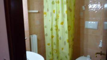 Ein Badezimmer mit gelbem Duschvorhang, Toilette und Waschbecken, alles in Weiß.