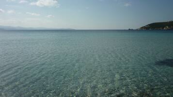 A clear view of a calm sea with a distant coastline and mountains.