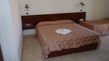 Habitación de hotel con dos camas, cabecero de madera, teléfono y lámpara fijada a la pared.