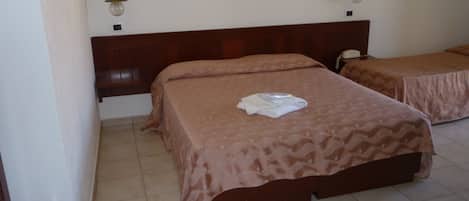 A hotel room with two beds, a wooden headboard, a telephone, and a wall-mounted light fixture.