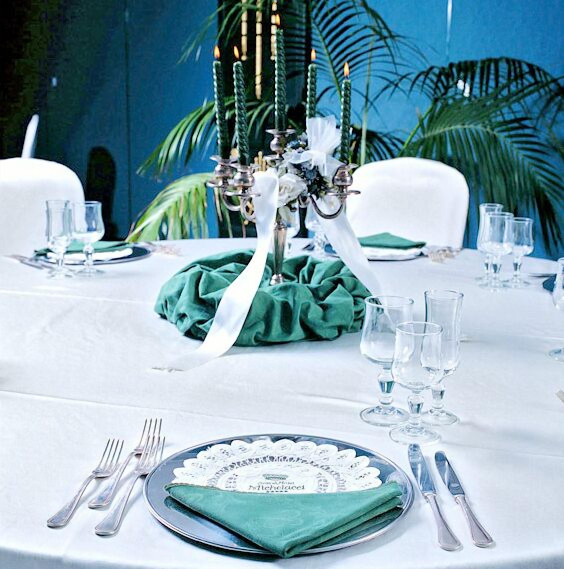 A table set with a green napkin, white tablecloth, and clear glassware.