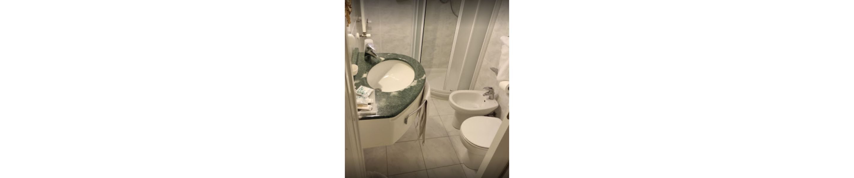 Une salle de bain avec un lavabo en marbre, un bidet et des toilettes.