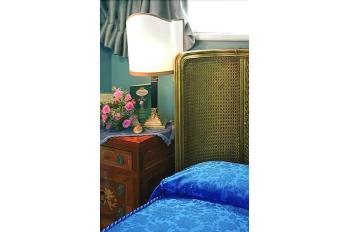 A room with a bed, a dresser, a lamp, and a window with curtains.