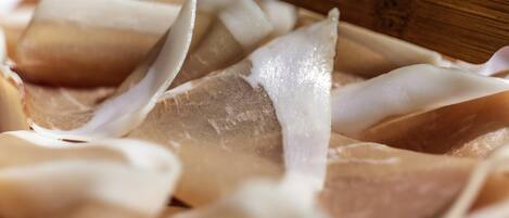 A close-up of a wooden cutting board with a white, translucent material, possibly cheese or a similar food item, on it.