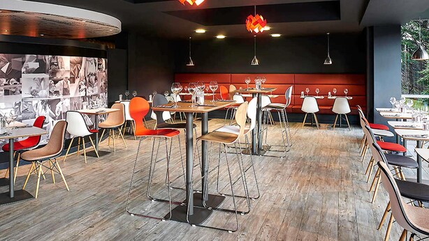 A modern restaurant interior with high tables, bar stools, and pendant lighting. - ibis Swansea (Swansea)
