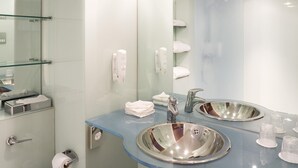 A modern bathroom with a glass shower enclosure, a double sink with a stainless steel basin, and a glass partition. - ibis Swansea (Swansea)