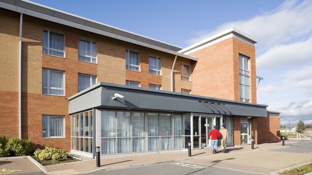 A modern building with a brick facade, large windows, and a covered entrance area. - ibis Swansea (Swansea)