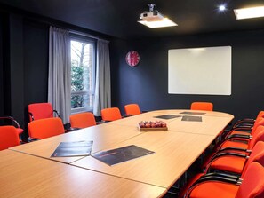 A conference room with a long table, orange chairs, a projector, a clock, and a whiteboard. - ibis Swansea (Swansea)