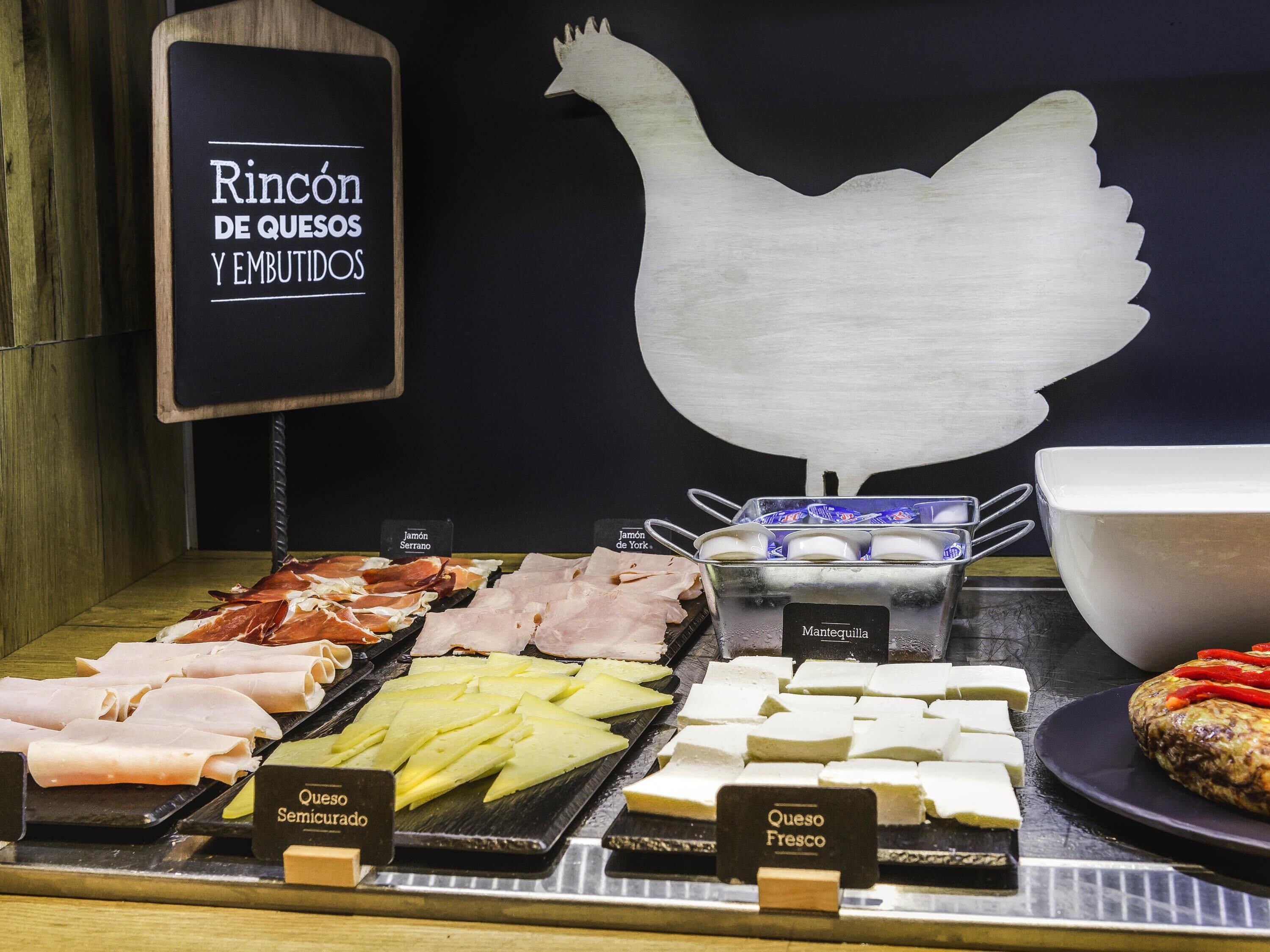 A cheese and cured meat display with labels for different types.