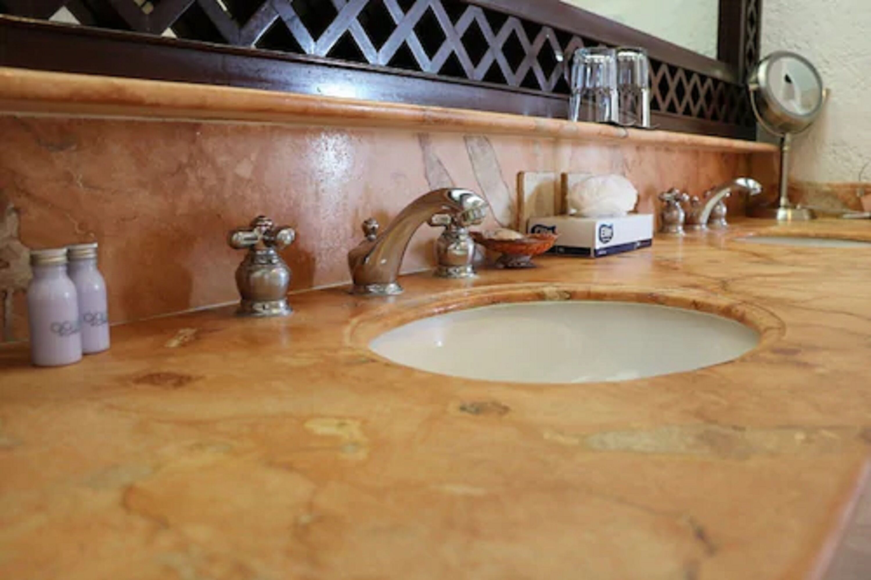 Une salle de bain avec un lavabo en marbre, deux robinets et un miroir.