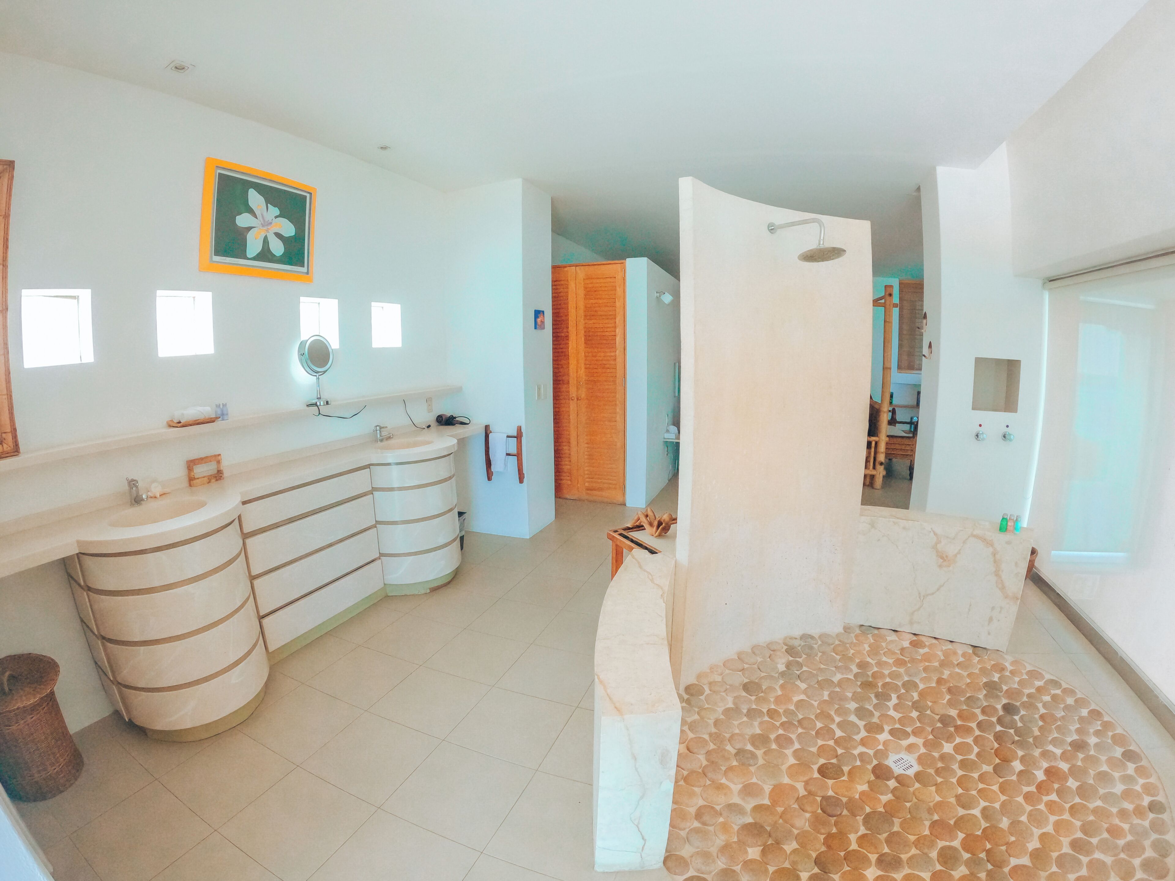 A bathroom with a curved sink, a mirror, and a shower area.