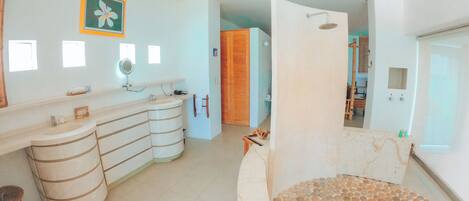 A bathroom with a curved sink, a mirror, and a shower area.