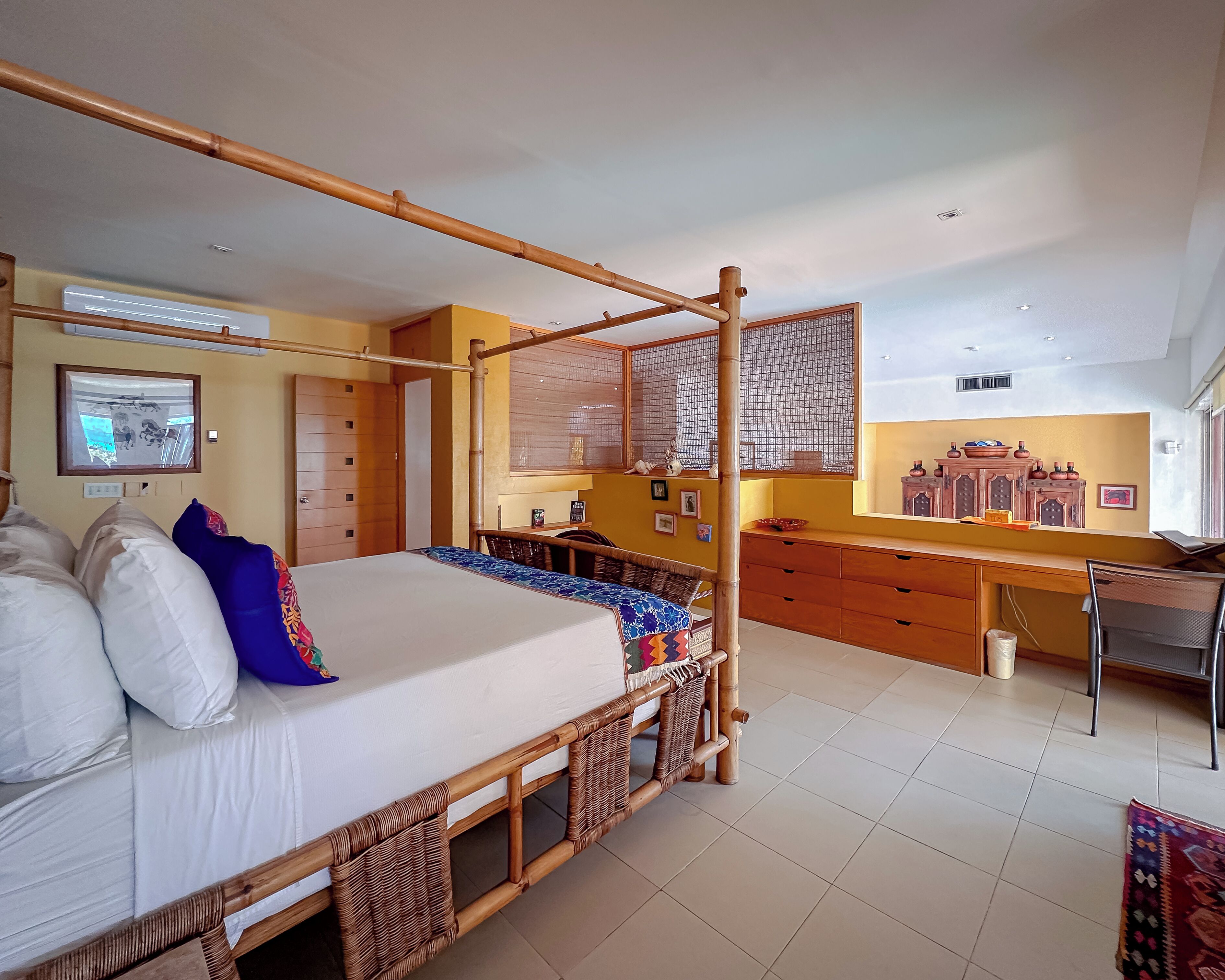 A room with a four-poster bed, a desk, and a chair.