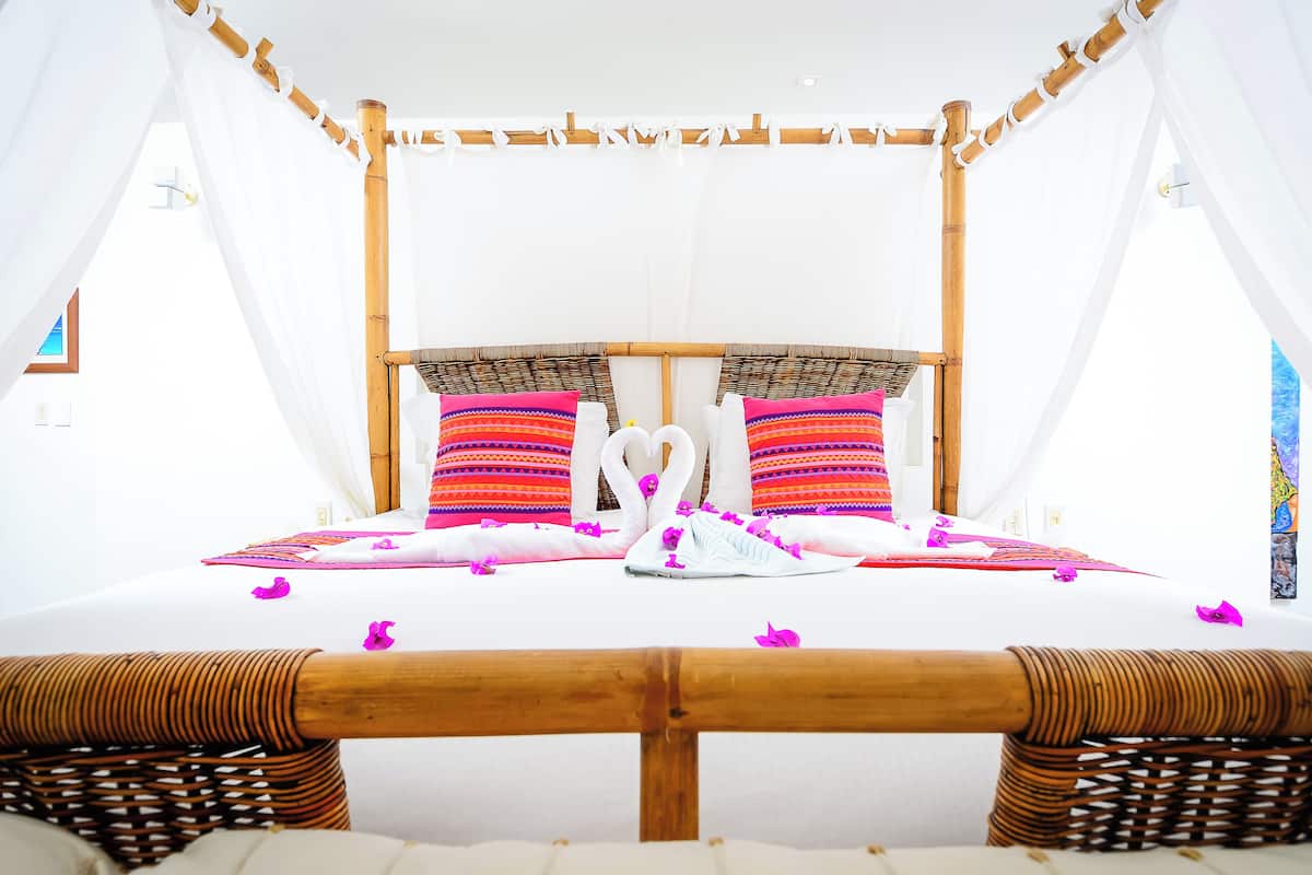 Una cama con dosel, dos almohadas y una decoración con forma de cisne.