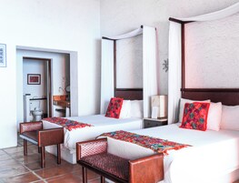 Habitación de hotel con dos camas, zona de estar, baño y un pequeño escritorio.