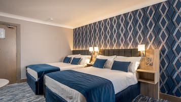 Habitación de hotel con dos camas, una mesita de noche de madera y un papel tapiz estampado.