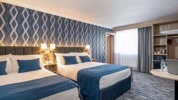 A hotel room with two beds, a desk, a laptop, and a wardrobe.