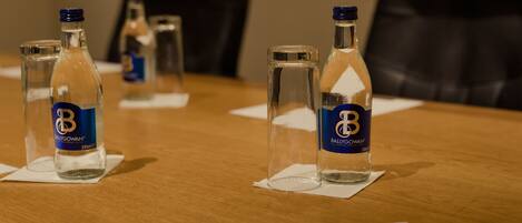 A conference table with bottles of Ballygowan water, a pen, and papers.