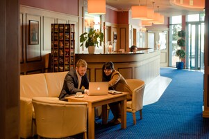 A lobby with a reception desk, seating area, and a large potted plant.