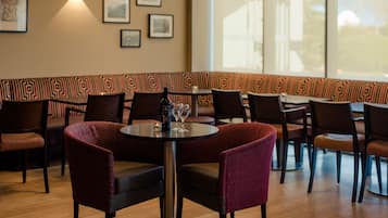 En restaurang med avskilda sittplatser i form av bås, bord med stolar och inramade tavlor på väggen.