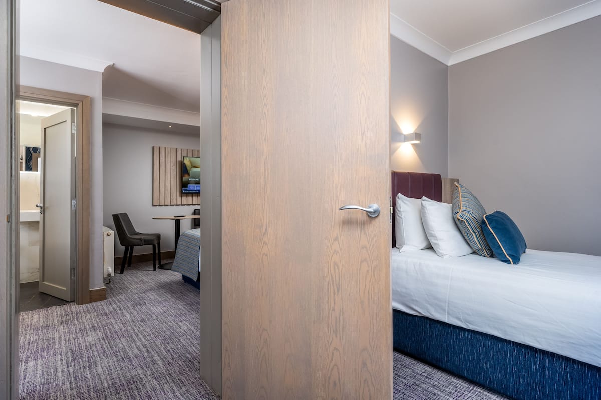 Una habitación de hotel con cama, escritorio y una silla.