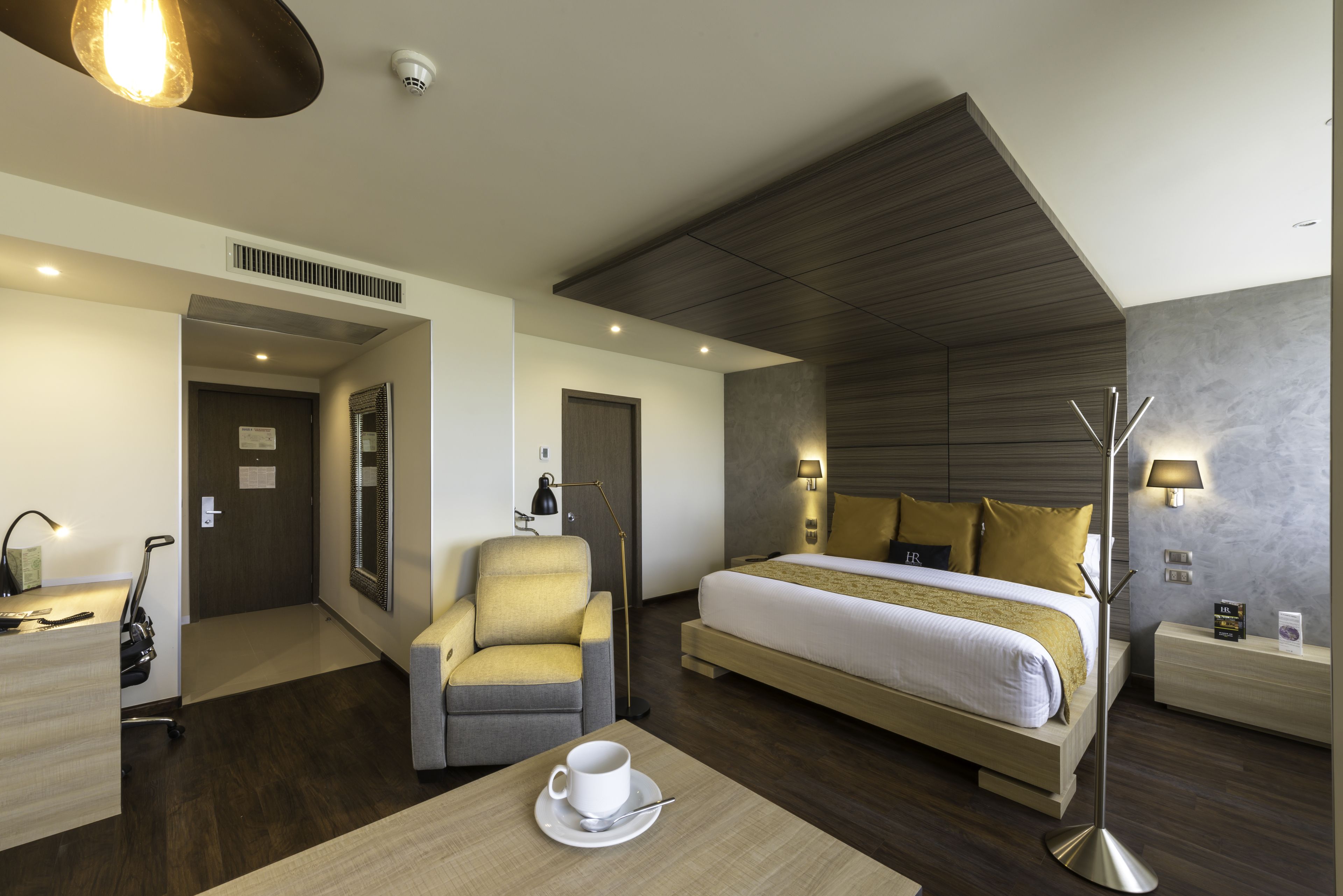 Una habitación de hotel con cama, escritorio, silla, mesa de centro y lámpara.
