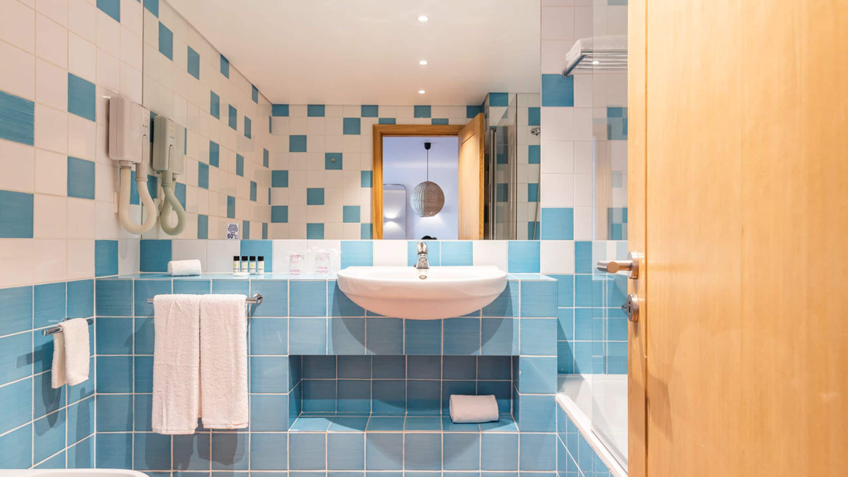 Une salle de bain équipée d’un lavabo, de deux serviettes, d’un miroir et d’un espace douche.
