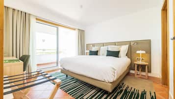 Habitación de hotel con una cama grande, un escritorio, una silla, una mesita con una lámpara y vistas al exterior.