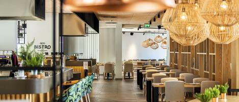 Een restaurant met een bar, houten tafels en hangende lampen.