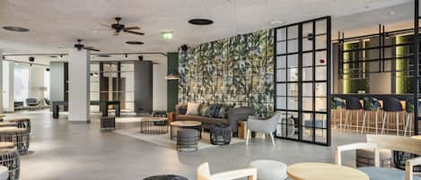 A spacious indoor area with ceiling fans, seating arrangements, and a patterned wall.