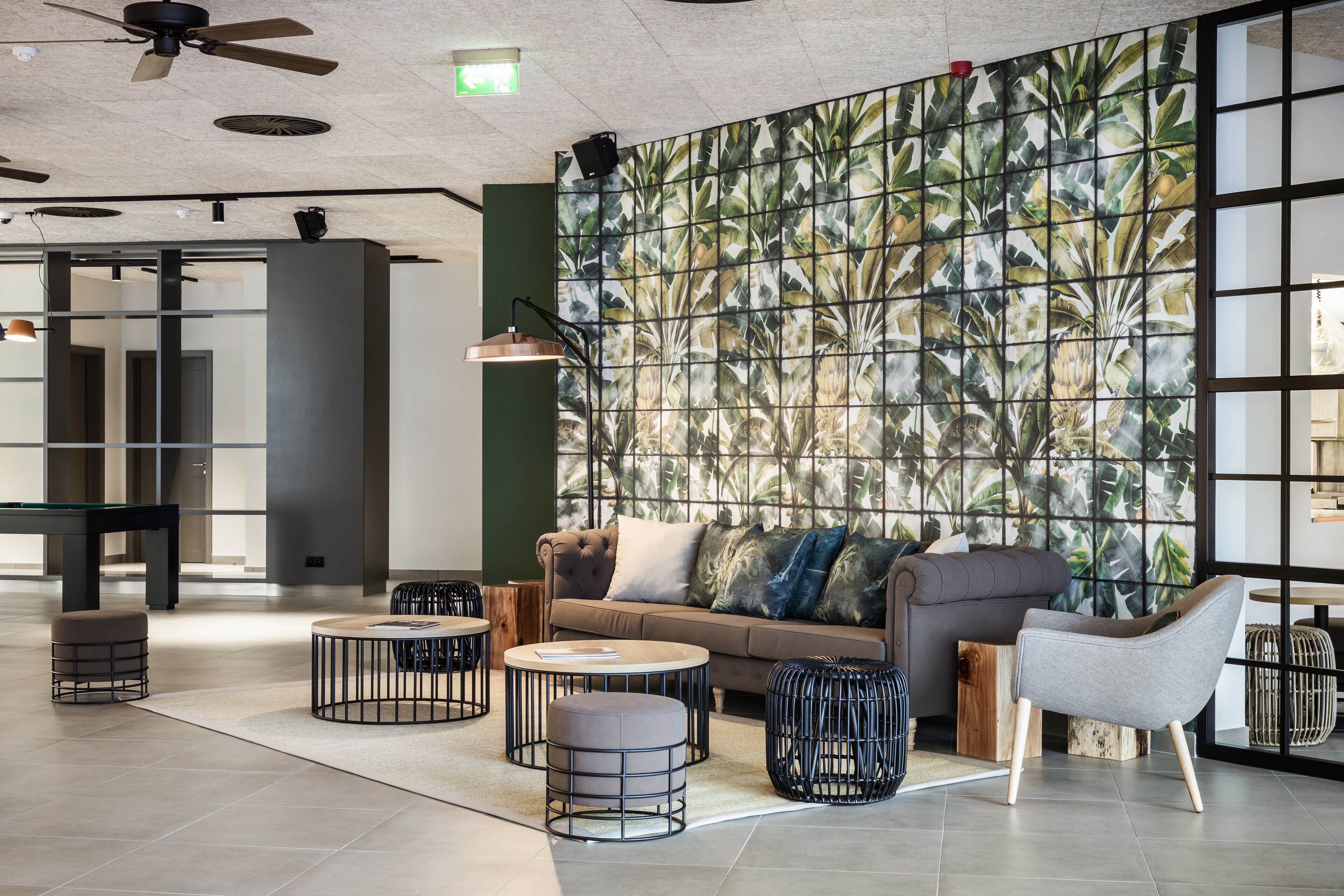 Un espace de détente moderne comprenant un canapé, un pouf rond et un fauteuil.