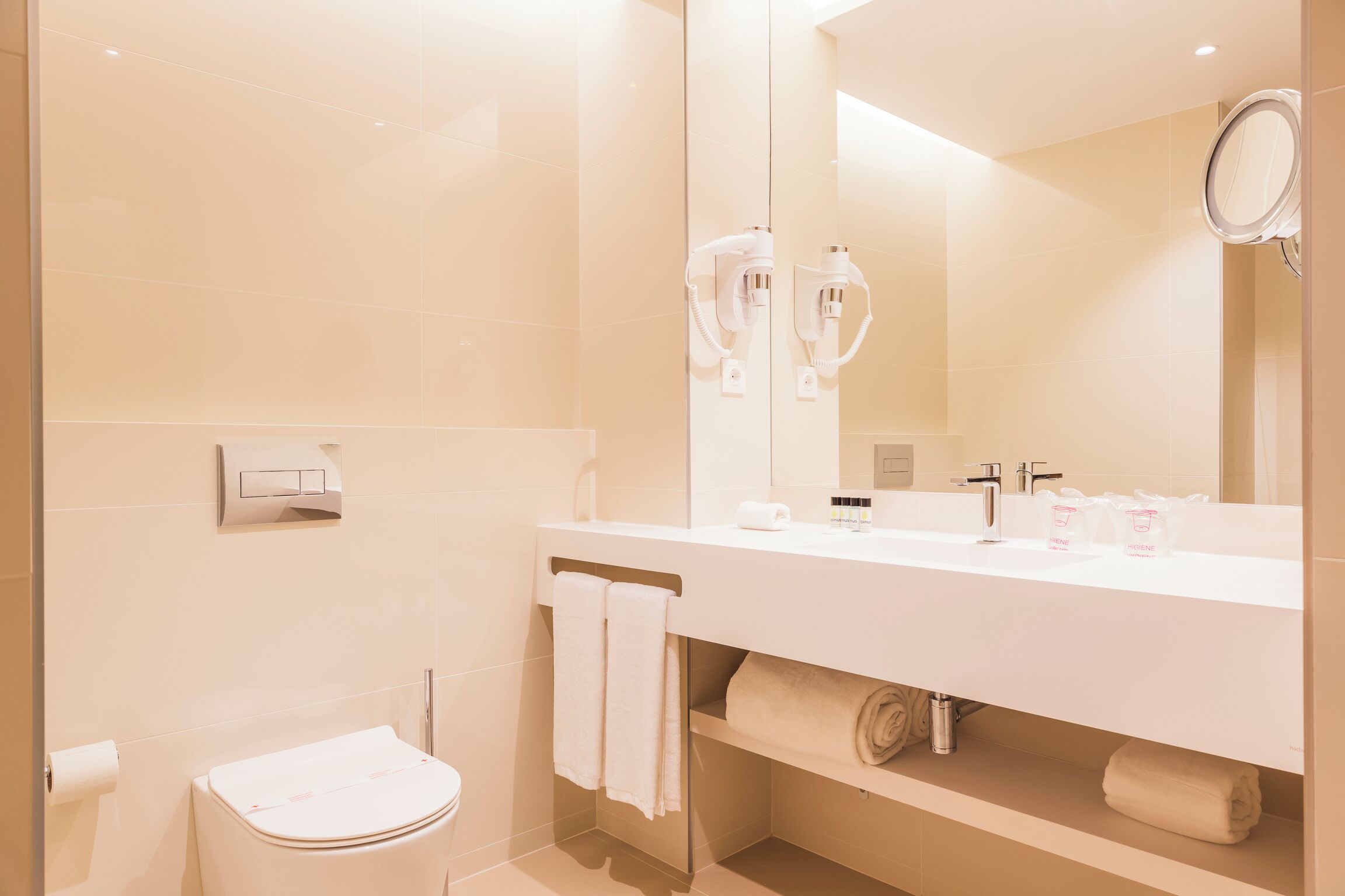 Une salle de bain moderne avec un lavabo blanc, un grand miroir et des toilettes.