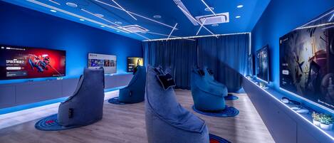 A modern room with a large flat-screen TV displaying a movie, bean bag chairs, and a wooden floor.
